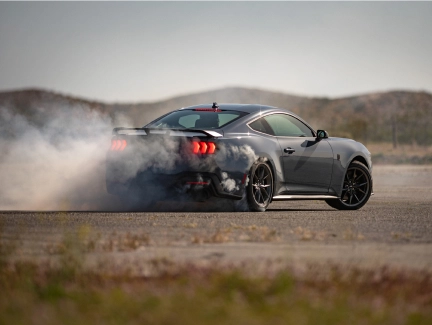 Mustang drifting, smoke billowing from the tires, demonstrating performance and handling.