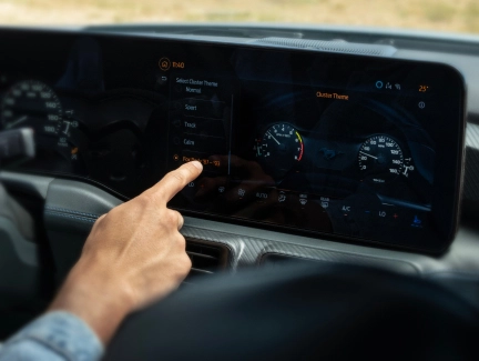A hand interacting with the large touchscreen infotainment system in the Ford Mustang, emphasising the immersive and user-friendly interface.